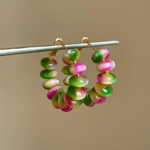 Close-up of rainbow gradient resin bead hoop earrings with golden finish