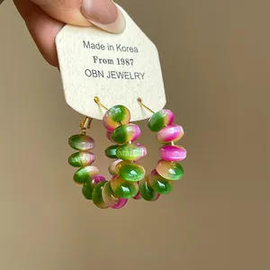 Close-up detail of gradient resin beaded hoop earrings featuring vibrant rainbow colors