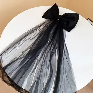Barrette à cheveux élégante avec grand nœud en tissu noir et longs voiles en tulle.