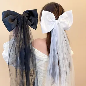 Détail de grandes barrettes nœuds en tissu noir et blanc avec rubans en tulle