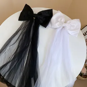 Détail de pinces à cheveux avec nœuds en tissu blanc et noir et longs voiles en tulle