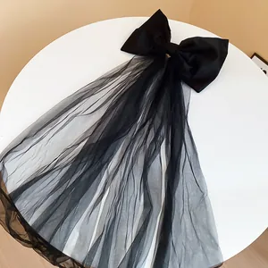Noeud papillon en tissu noir élégant avec un long détail de voile en tulle fluide.