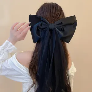 Détail d'une grande pince à cheveux nœud noir en tissu avec d'élégants glands en tulle mesh