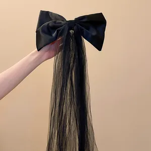 Détail de la pince à cheveux noeud en satin noir avec longues franges en tulle.