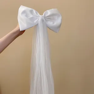 Gros plan d'une élégante pince à cheveux à nœud en satin blanc avec pompons en tulle