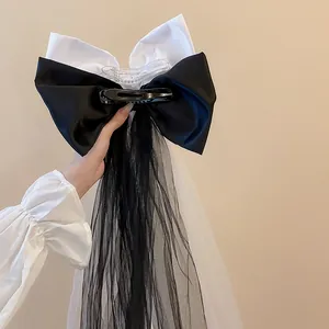 Gros plan d'un nœud papillon en satin noir et blanc avec de longs rubans en tulle.