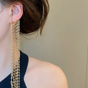 Gros plan sur un élégant earcuff à pampilles dorées avec de longues chaînes de perles