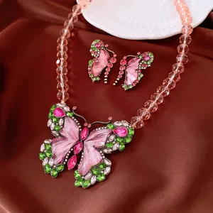 Macro view of vintage butterfly jewelry set with pink and green rhinestones on brown fabric
