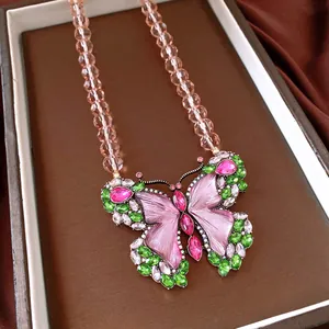 Macro view of vintage butterfly necklace featuring pink and green rhinestones and beaded chain