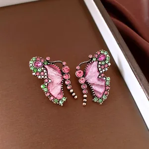 Detailed macro view of vintage butterfly stud earrings featuring pink wings and crystals
