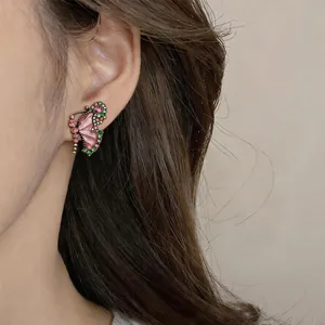 Close-up view of vintage style butterfly earrings with pink and green crystals on model