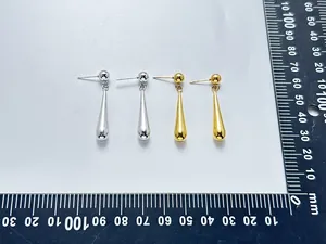 Gros plan des boucles d'oreilles goutte en acier montrant la mesure de longueur