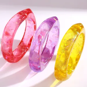 Makroaufnahme bunter Harzarmreifen mit schillernden Glitzerflocken und Geometrie-Stil