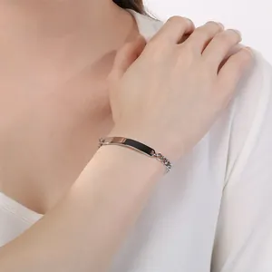 Dettaglio di un bracciale a catena cubana in acciaio con barra curva nera sul polso.