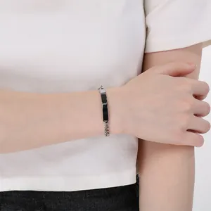 Dettaglio di un bracciale a catena cubana argento con una piastra nera incidibile sul polso
