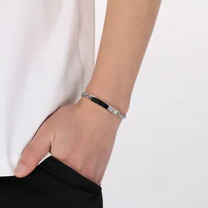 Vista dettagliata di un bracciale a catena cubana in acciaio al titanio con piastra incisa.