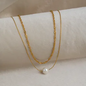 Détail d'un élégant collier doré à deux rangs avec un pendentif en perle unique