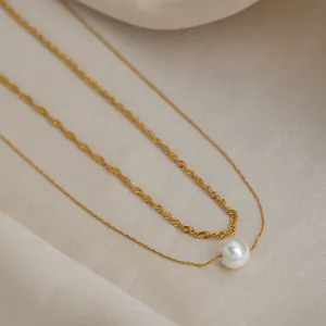 Gros plan d'un collier double couche plaqué or 18 carats avec une perle blanche élégante.