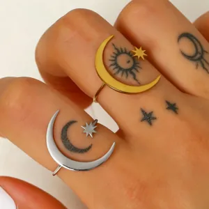 Close-up of stainless steel gold and silver crescent moon and star rings on tattooed fingers
