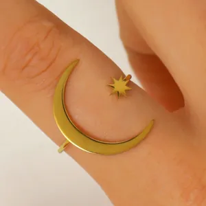Close-up detail of a gold stainless steel crescent moon and star open ring on a finger