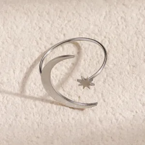 Close-up of a silver stainless steel moon and star open ring on a textured background