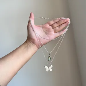 Close-up of vintage silver layered necklace with waterdrop and butterfly pendant