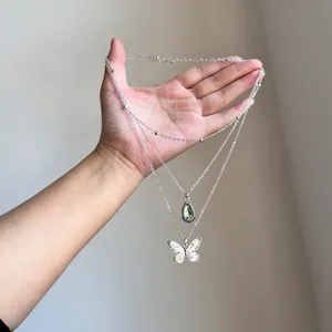 Detail of vintage layered necklace featuring a resin teardrop and white butterfly pendant.