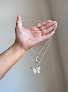Close-up of silver-toned multi-layer necklace with butterfly and resin teardrop.