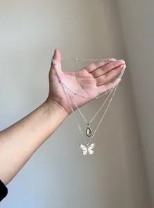 Vintage layered necklace with silver butterfly and green resin water drop pendants.