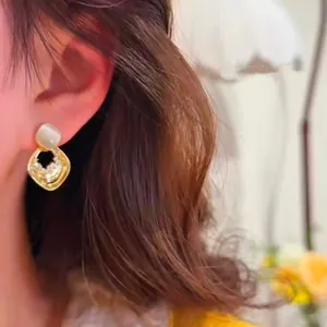 Detail view of French style golden rhombus earrings with cat eye stone and zircon crystals
