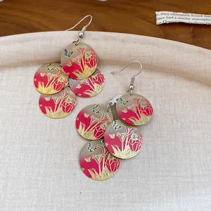 Vista detallada de pendientes vintage de esmalte con flores rojas y mariposas