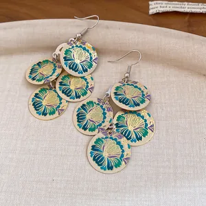 Detalle de pendientes vintage con flores esmaltadas y borlas redondas oro