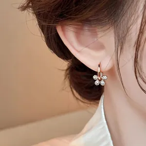 Gros plan d'une boucle d'oreille en zircon plaquée or 14 carats portée à l'oreille d'un mannequin