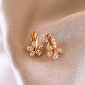 Gros plan de boucles d'oreilles fleur plaquées or 14k avec des oxydes de zirconium.