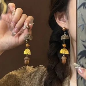 Macro detail of ethnic style wooden acorn drop earrings with vintage golden accents