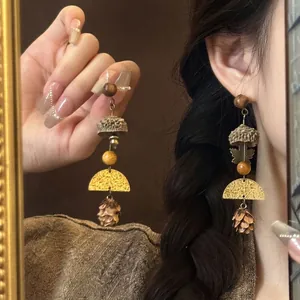 Detail of ethnic earrings featuring wooden beads, pine cone pendants, and gold accents