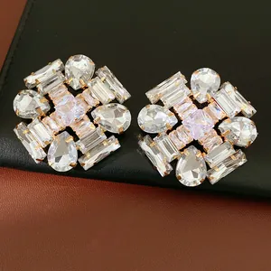 Close-up detail of geometric stud earrings with sparkling teardrop and rectangular zircons
