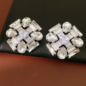Macro view of exaggerated earrings featuring teardrop and rectangular clear crystals
