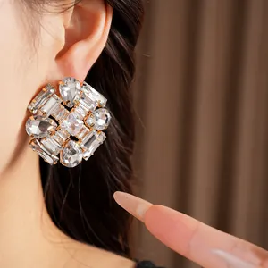 Close-up detail of oversized crystal cluster stud earrings with gold-toned finish