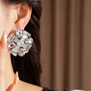 Close-up view of glamorous clear crystal cluster stud earrings worn by a model.