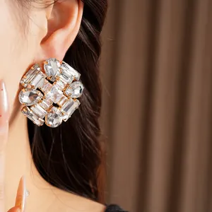 Detailed macro view of oversized silver needle stud earrings with teardrop crystals