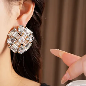 Close-up of exaggerated rhinestone stud earrings with teardrop and rhombus crystals