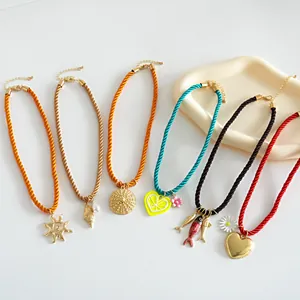 Detail view of colorful vacation style rope necklaces with various metal drip oil charms
