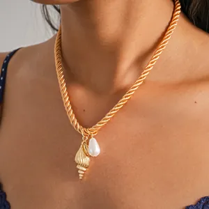 Detailed close-up of a gold rope chain necklace with a shell and pearl pendant