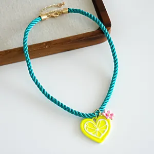 Detailed view of a turquoise twisted rope necklace with heart lemon and flower charms.