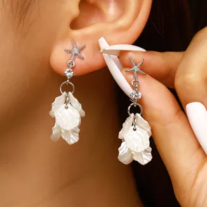 Elegant silver starfish stud earrings featuring white acrylic petals and rhinestones