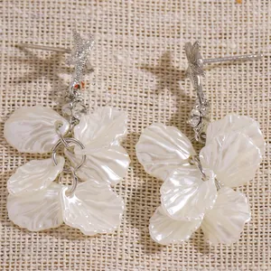Detailed macro view of silver starfish studs with elegant white shell flower petal dangles