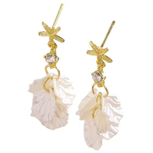 Detailed view of elegant golden starfish earrings featuring white shell petal tassel drops