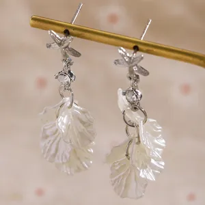 Close-up of French style starfish and white shell petal tassel earrings with crystals.