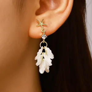 Close-up of elegant French style earrings with starfish and white petal tassels
